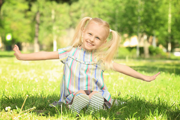 Canvas Print - Cute little girl sitting on green grass in park