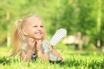 Canvas Print - Cute little girl lying on green grass in park