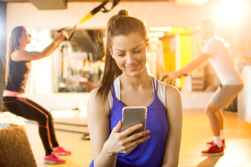 Wall Mural - Girl texting while taking a break in a gym.