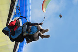 Two paraglider tandem fly against the blue sky,tandem paragliding guided by a pilot