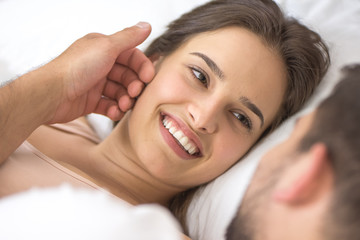 The man touch a face of woman in the bed