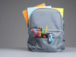 Backpack with school supplies on grey wooden table