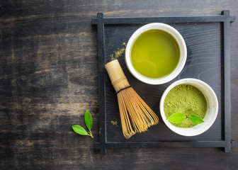 Wall Mural - Green matcha tea in a bowl and bamboo whiskon on wood table,top view