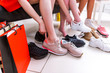 © undrey - Close-up photo of female legs choosing sports footwear trying on different sneakers in a shopping mall