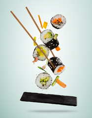 Poster - Flying sushi pieces served on stone plate, separated on soft background