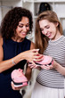 © undrey - Two smiling women holding new pair of sports footwear looking at price label standing in boutique