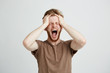 © Cookie Studio - Portrait of emotional upset angry man shouting screaming holding head over white background.