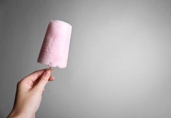 Sticker - Female hand holding sweet cotton candy on color background