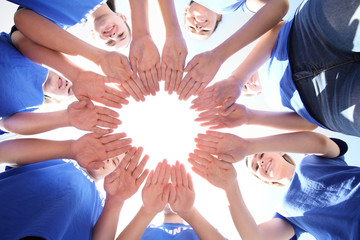 Sticker - Team of volunteers putting their hands together as symbol of unity, bottom view