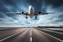 Airplane And Road With Motion Blur Effect. Landscape With White Passenger Airplane Is Flying In The Cloudy Sky Over The Asphalt Road. Blurred. Passenger Airplane Is Landing. Commercial Plane. Aircraft