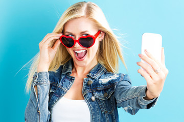 Sticker - Young woman taking a selfie on a blue background