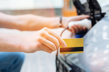 Male Hand Holding A Credit Card While Charging An Electric Car