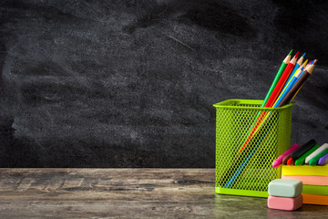 school supplies on wooden table and blackboard background. back to school concept. copyspace.