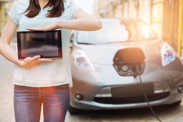 Female holding a tablet in front of her car