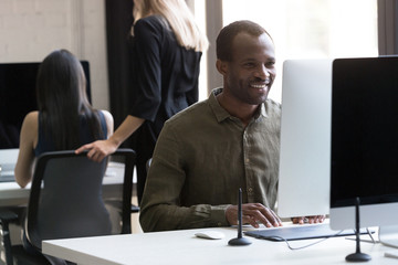 Wall Mural - Smiling african american businessman working on his computer