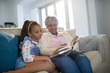 © WavebreakMediaMicro - Grandmother and daughter reading book in living room