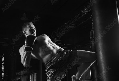 Leinwand Poster The fighter of mixed martial arts with a shout is hitting the bag