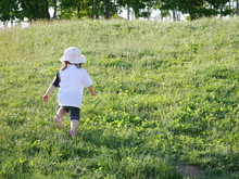 An Infant Girl Trying To Climb A Small Grassy Hill