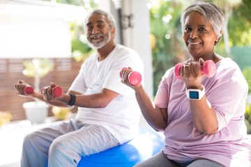 Portrait of smiling couple lifting dumbbells