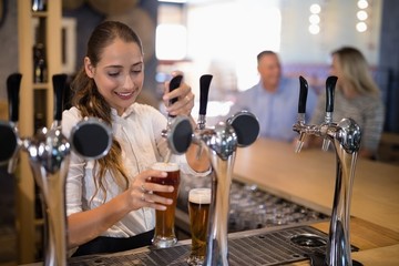 Wall Mural - Female bartender filling beer from bar pump