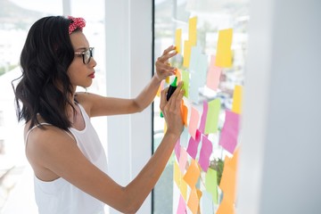 Wall Mural - Female executive writing on sticky notes