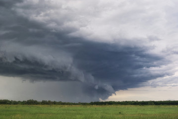 storm cyclone over summer fields, hills and forests