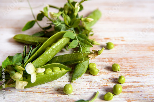 Fototapeta na szkło fresh green peas, peas flowers and leaves on wooden background, flat lay, top view