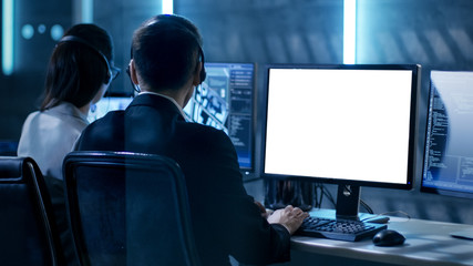 Aufkleber - Shot of Young Female Government Employee Wearing Glasses Uses Tablet in System Control Center. In the Background Her Coworkers are at Their Workspaces with many Displays Showing Valuable Data.