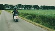 Young girls riding scooter on country road