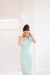 © Taras - Female model wearing tender turquoise dress, holding hands on the neck.