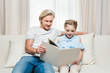 © LIGHTFIELD STUDIOS - happy father and daughter reading book while sitting on sofa at home