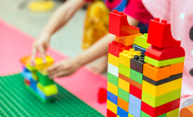 Preschooler child playing with colorful toy blocks. Preschool children build tower with plastic block. Toddler kid in nursery.