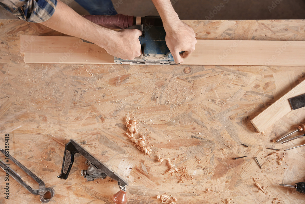 Carpenter working with grinder in shop