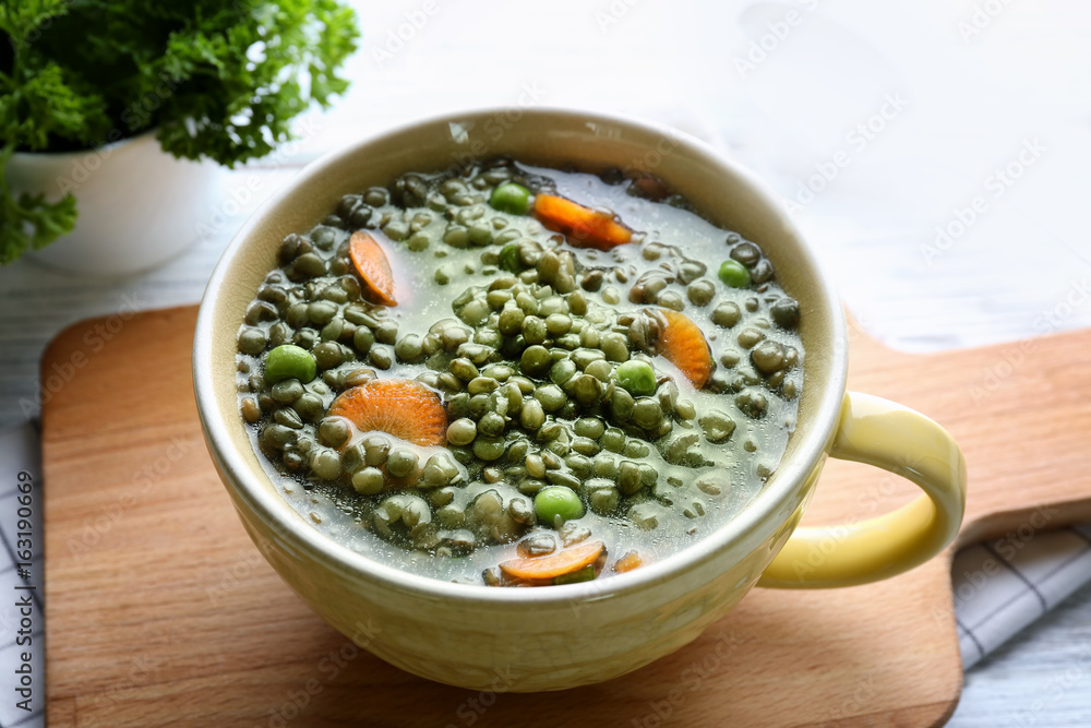 Soup cup with tasty lentil dish on kitchen table, closeup