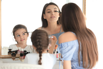 Sticker - Young woman and her little daughter applying makeup at home