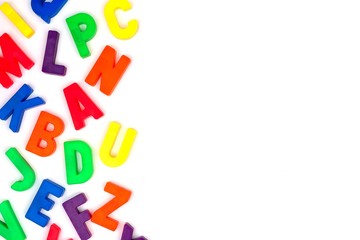 Wall Mural - Side border of colorful toy magnetic alphabet letters over a white background