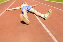 An Exhausted Athlete On A Running Track Wearing Broken Green Running Shoes With Big Holes In The Sole.