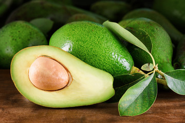 Canvas Print - Ripe green avocados with leaves on wooden table