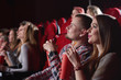 © serhiibobyk - Beautiful young woman smiling sitting next to her boyfriend at the cinema. Loving couple watching a movie together couples dating people friendship leisure entertaining.