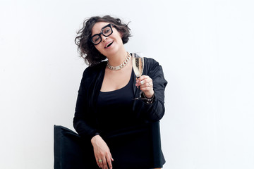 Portrait of young plus size model with fashionable glasses dressed in black holding a glass of champagne. Composition with copy space.