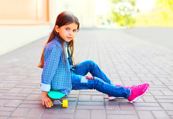 Wall Mural - portrait beautiful little girl child sitting on the skateboard in the city