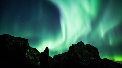 Wall Mural - glowing aurora borealis over volcanic rock formations time lapse 4k