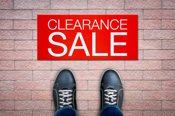 Wall Mural - Black shoes standing on tiled brick floor with clearance sale advertisement billboard.