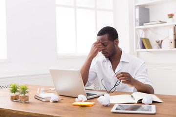 Wall Mural - Tired african-american employee in office, work with laptop