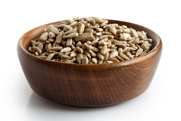 Wall Mural - Peeled dry sunflower seeds in dark wooden bowl isolated on white.