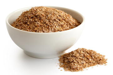 Wheat bran  in white ceramic bowl isolated on white. Spilled bran.