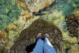 Fototapeta  - Męskie nogi na ogromnym kamieniu, nad brzegiem morza. 