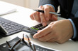 © everythingpossible - close up of businessman hand working with finances about cost and calculator and latop with mobile phone on withe desk in modern office