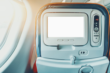 Empty white mock-up of aircraft multimedia screen with remote control, close-up view of blank placeholder of airplane monitor filled with solid white in passenger seat, multiple buttons and sockets