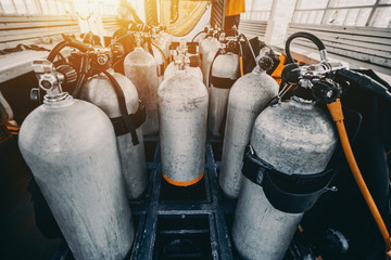 Wide angle view of numerous oxygen and nitrox dive tanks standing on the bottom of deck on diving boat ready for use for two tanks dive - every second container is with connected equipment and suit